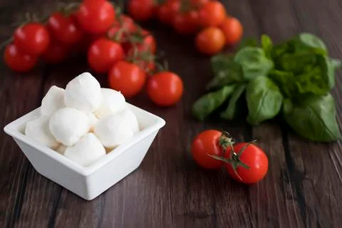 Mozzarella cheese, basil and cherry tomatoes on  brown wooden table. Ingredie Stock Photos