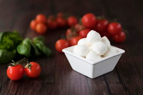 Mozzarella cheese, basil and cherry tomatoes on  brown wooden table. Ingredie Stock Photos
