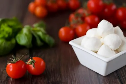 Mozzarella cheese, basil and cherry tomatoes on  brown wooden table. Ingredie Stock Photos