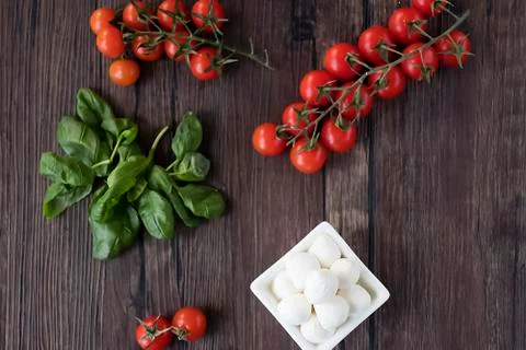 Mozzarella cheese, basil and cherry tomatoes on  brown wooden table. Ingredie Stock Photos