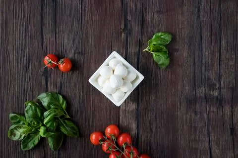 Mozzarella cheese, basil and cherry tomatoes on  brown wooden table. Ingredie Stock Photos