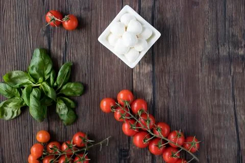 Mozzarella cheese, basil and cherry tomatoes on  brown wooden table. Ingredie Stock Photos