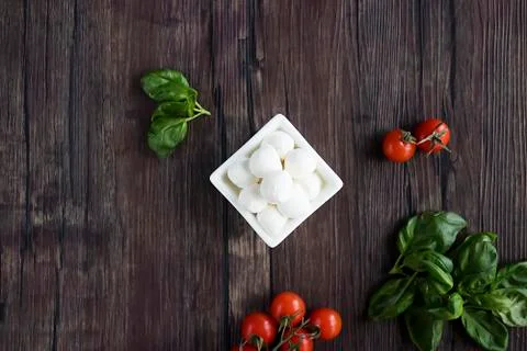 Mozzarella cheese, basil and cherry tomatoes on  brown wooden table. Ingredie Stock Photos