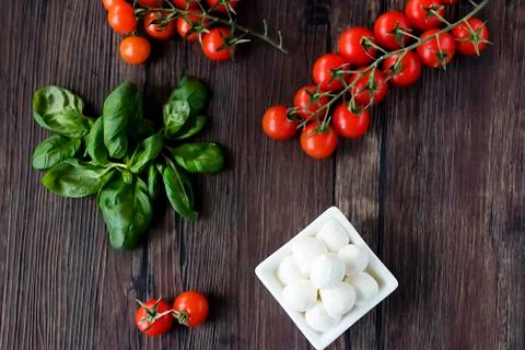 Mozzarella cheese, basil and cherry tomatoes on  brown wooden table. Ingredie Stock Photos