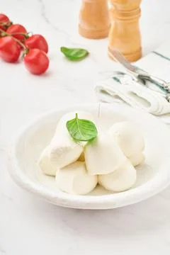 Mozzarella cheese with basil in white ceramic plate and tomato cherry on slat Stock Photos