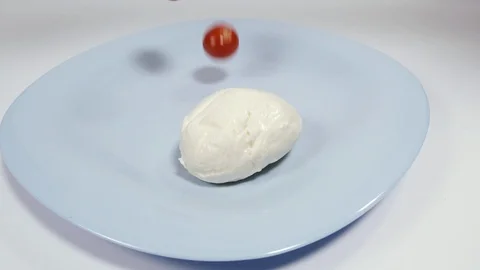 Mozzarella cheese. Tomatoes fall on a plate with mozzarella cheese. Shot in s Stock Footage 128939745