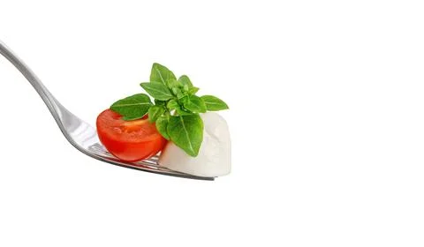 Mozzarella on a fork close up. Mozzarella cheese with tomato and green basil  Stockfoto's