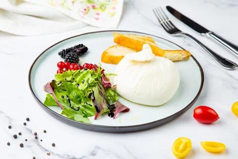 Mozzarella with spinach, cherry tomatoes, wild berries and bread in a round Stock Photos