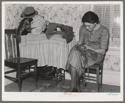 Mrs. Gallagher patching clothes for her children. Wife of former farmer, n... Stock Photos