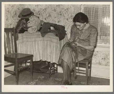 Mrs. Gallagher patching clothes for her children. Wife of former farmer, n... Stock Photos