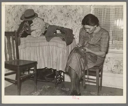 Mrs. Gallagher patching clothes for her children. Wife of former farmer, n... Stock Photos