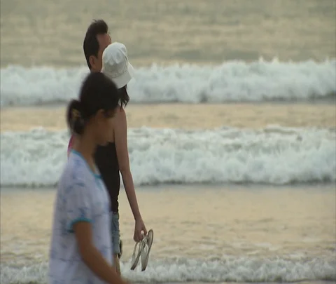MS couple walking on beach with waves rolling in Stock Footage 86747303