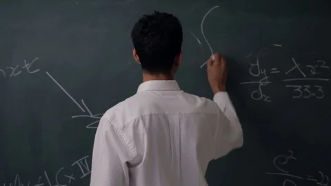 MS Man writing on blackboard turns, looking at camera Stock Footage 69937566