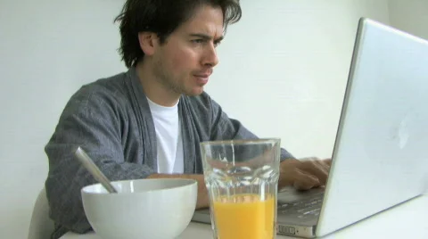 MS PAN OF A MAN HAVING BREAKFAST AND USING LAPTOP Stock Footage 543266