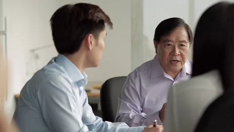 MS SELECTIVE FOCUS Senior businessman speaking to two colleagues at meeting / Stock Footage 69938356