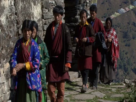 MS Villagers walking on mountain path past stone temple. Stock Footage 86748853