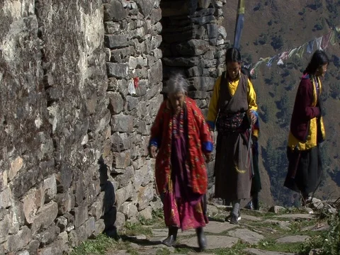 MS Villagers walking on mountain path past stone temple. Stock-Footage 86748856