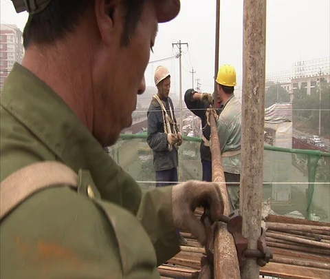 MS workers in hard hats secure scaffolding atop construction site Stock Footage 86744328