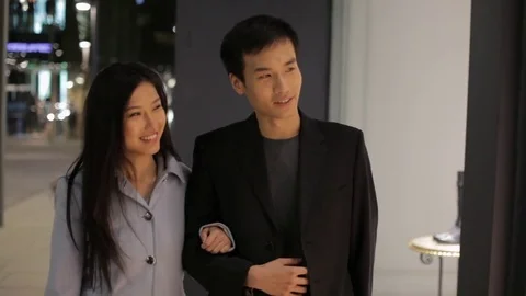 MS Young couple walking and talking on street at night / China Stock Footage 69943763
