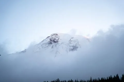 Mt. Rainier poking through the clouds amidst Mt. Rainier National Park. Stock Photos