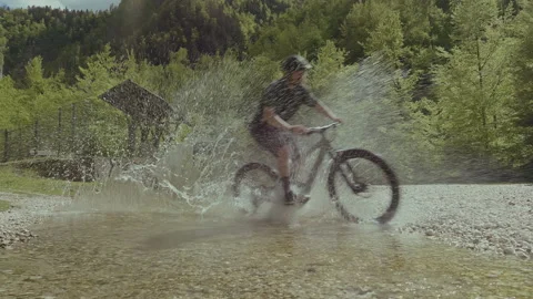MTB E-bike biker riding through the river stream and splashing the camera. Stock Footage 131078727