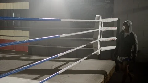 Muay Thai fighter in hand wraps and hoodie walks into boxing ring 스톡 동영상 104580238