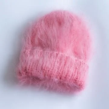 Much fluffy and warm hat pink knitted by hand on a white background Stock Photos