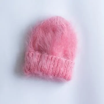 Much fluffy and warm hat pink knitted by hand on a white background Stock Photos