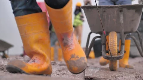Mud boots pulling a wheelbarrow on a construction site front view Stock Footage 158740651