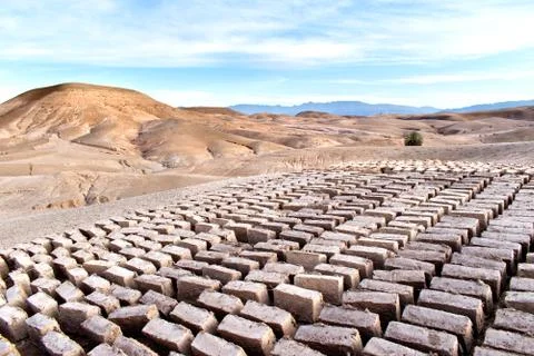 Mud bricks drying in the Moroccan desert with sand dunes in the background Stock Photos
