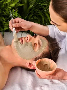 Mud facial mask of woman in spa salon. Face massage . Stock Photos
