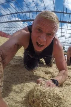 Mud race runners. Crawling,passing under a barbed wire obstacles during extreme Stock Photos