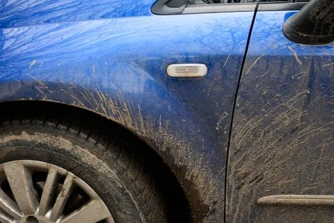Mud splashes on the side of blue car. Dirty vehicle during rainy weather Stock Photos