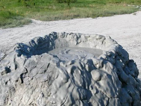Mud volcano flowing down clayey mud mixed with hydrocarbons. Stock Photos