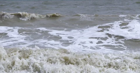 Muddy brown ocean waves breaking with white foam bubbles splashing water near 库存影片 348777066