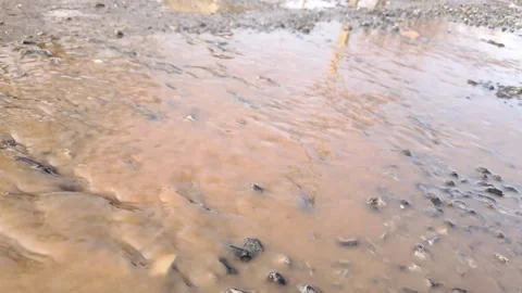 Muddy brown water flowing in a puddle on a dirt road. Stock Footage 329971288