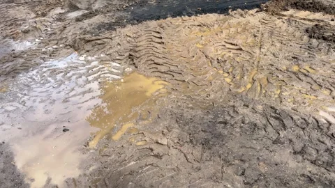 Muddy dirt road with deep heavy tire tracks and large puddles  库存影片 340261229