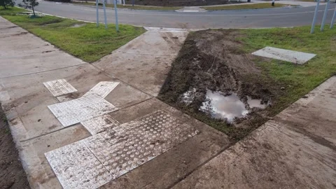 A muddy nature strip with a large puddle beside a suburban footpath Vídeos de archivo 312423662