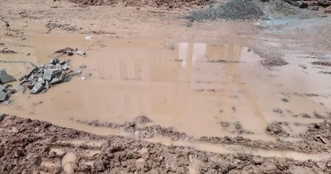 Muddy puddle on a construction site, filled by falling raindrops, Vídeos de archivo 335572628