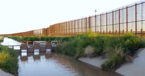 A Muddy River and Large Wall Separates Two Countries Stock Footage 67652247