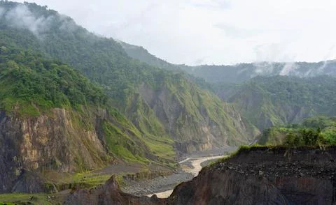 Muddy river beneath eroded cliffs and misty forest in Ecuador 写真素材