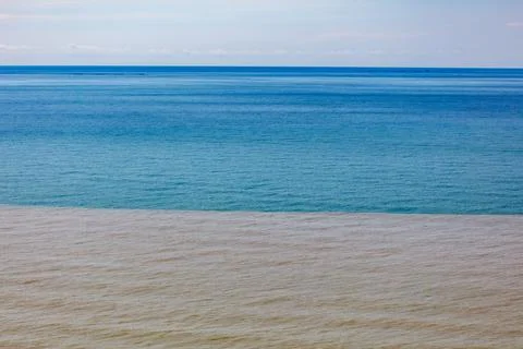 Muddy river current blends with blue sea water Foto stock