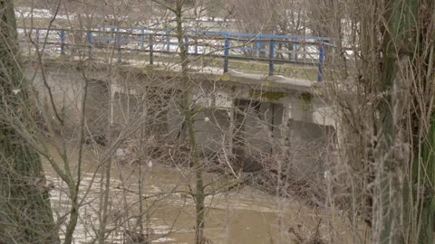 Muddy River Debris Clogging Bridge During Spring Thaw with Snow Stock Footage 336662760