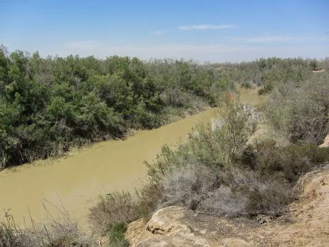A muddy river winding through trees Stock Photos