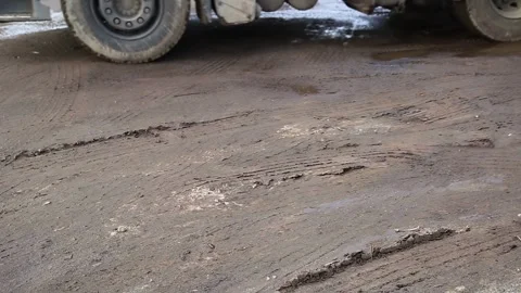 Muddy road surface with heavy vehicle tire tracks and puddles reflecting dull Stock Footage 323367142