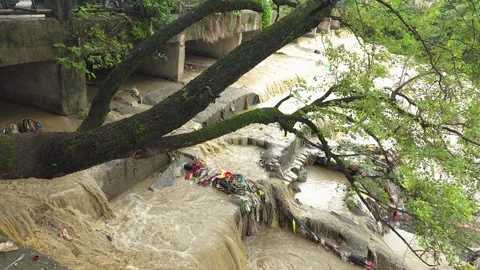 Muddy rushing river water after heavy rainfall under bridge the scene displays Видео 342586692