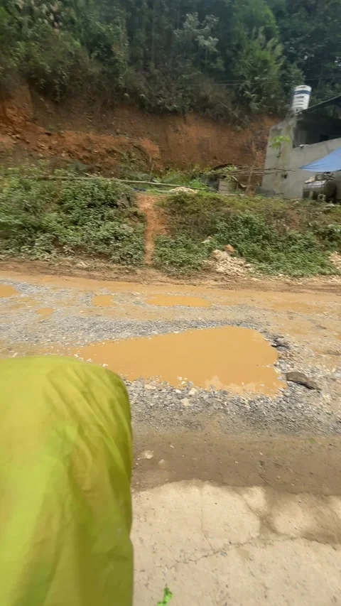Muddy unpaved mountain road with potholes and roadside forest in Ha Giang Stock Footage 336263907