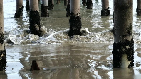 Muddy waves rolling in under a pier Stock Footage 134745305