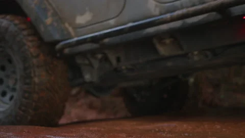 Muddy wheel driving over red dirt terrain in rain off-roading Vidéo 227586409