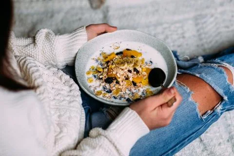 Muesli with banana, mango and chia seeds in a plate in a girl's hands Stock Photos